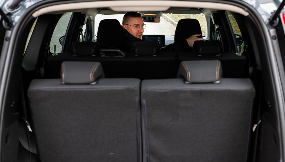 Bild tagen innifrån bagageluckan medan Johan tittar bakåt från förarstolen.