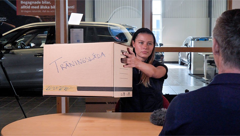 Tove Olsson, säljare på Bilbolaget Fyrislund, tränar på att flytta med en flyttkartong det står "Träningslåda" på