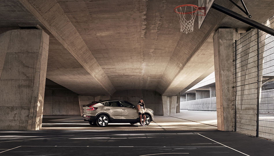 Kvinna som står med en basketboll vid sin Volvo EC40