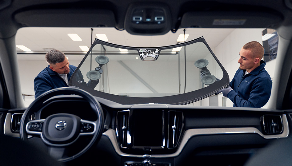 Två bilglasmästare som byter vindruta på bil