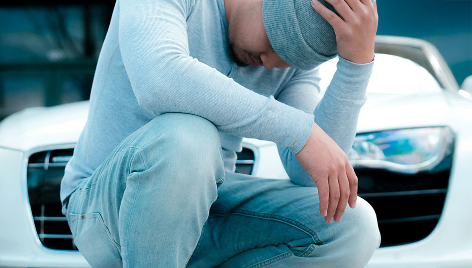 Kille som sitter framför sin bil och poserar som att han ser ledsen ut. Vi tror att han just insett hur taskig han varit som bara kört så korta sträckor med sin fina bil.
