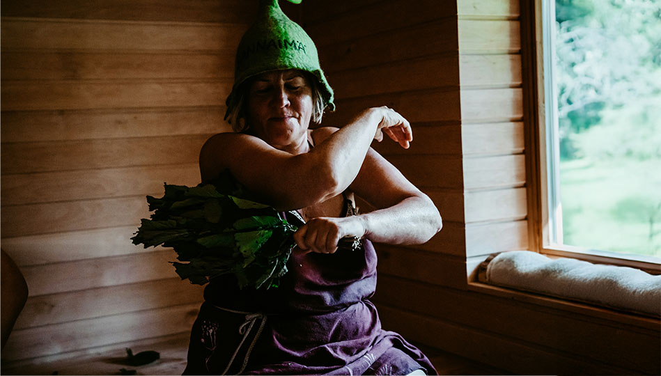 Kvinna i bastu med bastumössa och ris.