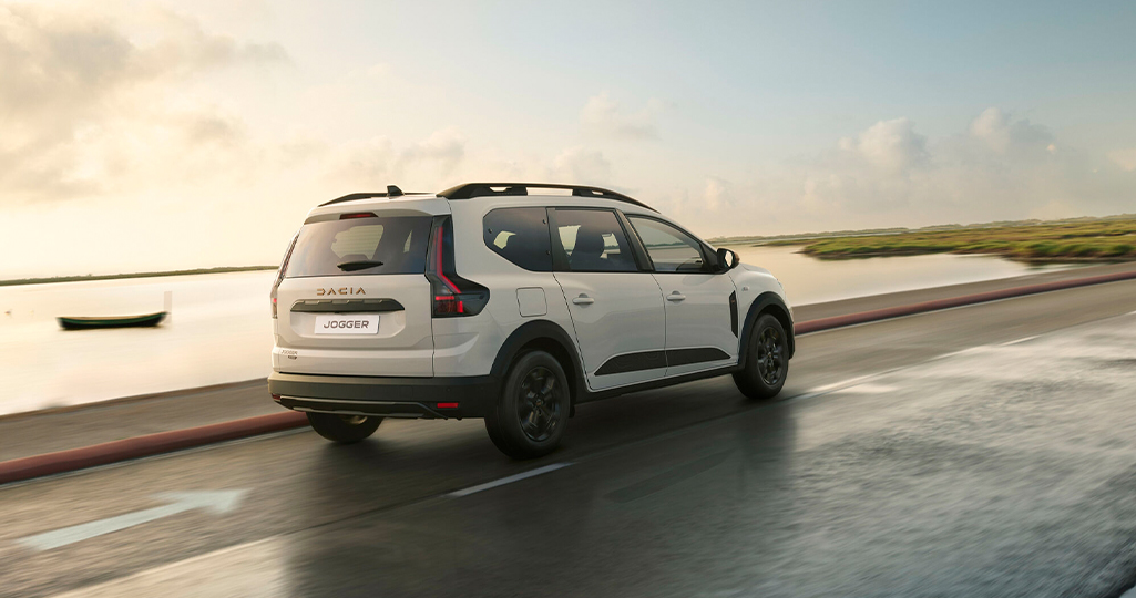 en Dacia Jogger sedd bakifrån när den kör på en väg längs vatten