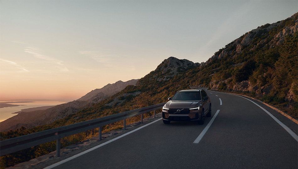 Volvo XC60 laddhybrid som ljudlöst rullar fram på en landsväg i bergen.