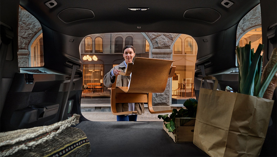 Kvinna som lastar in en stor i Volvo XC90s stora bagageutrymme.